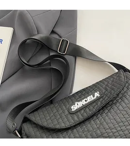 Detail of black quilted nylon crossbody bag with SMKCELA logo and adjustable strap