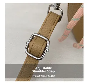 Detail view of adjustable leather strap with silver metal buckle on a khaki bucket bag
