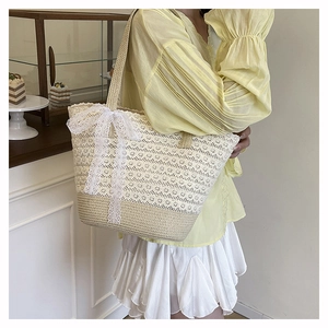Close-up of woven straw tote bag featuring white lace trim and a large bow detail