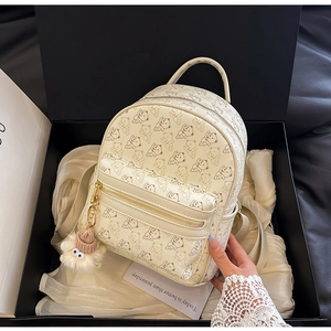 Detailed view of a beige bear print mini backpack in a luxury silk lined gift box