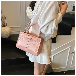 Détail d'un sac à main rose brillant avec boucles et rivets métalliques élégants