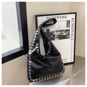 Detail view of black tote bag with silver metal rivets and polished leather texture