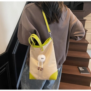 Canvas tote bag with green leather trim and cute plush charm on a model's shoulder