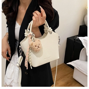 Detailed view of white litchi pattern tote bag with thick rope handle and cute bear charm