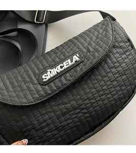 Close-up of quilted black nylon saddle bag with SMKCELA rubber logo and stitch detail