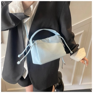 Detail of light blue lychee pattern leather bucket bag with pleated drawstring closure