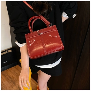 Détail du sac à main rouge foncé brillant avec boucle de ceinture et rivets argentés