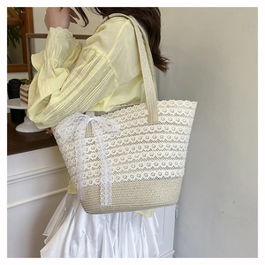 Detail of hand-woven straw tote bag with delicate white lace floral pattern and large bow