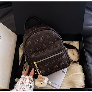 Mini brown backpack with golden bear print and plush bear charm in a black gift box