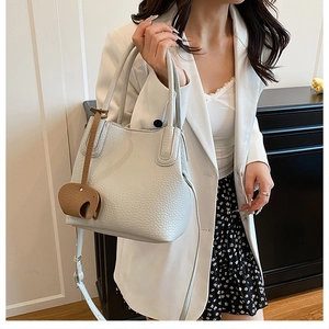 Détail d'un sac seau en cuir gris clair avec pendentif éléphant et bandoulière réglable