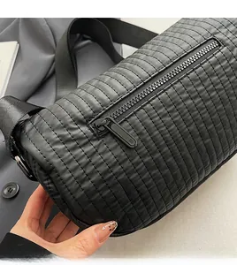Detail of smooth black zipper and horizontal quilted texture on cylindrical crossbody bag