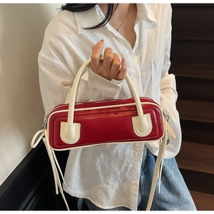 Detail of red and cream contrast leather handbag with side tassel and stylish top handles
