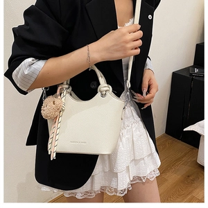 Detail view of cream white bucket bag with pebble leather texture and cute bear charm