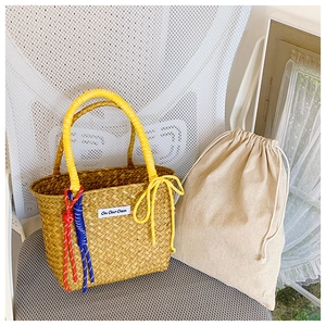 Detail of handmade straw tote with yellow handles and cotton drawstring inner bag