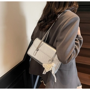 Detail of silver metallic shoulder bag with pearl heart and bow charm on a model