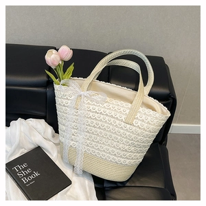 Detail of cream straw bucket bag with intricate lace floral overlay and lace bow accent