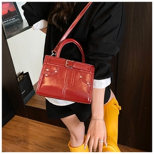 Sac à main chic en cuir verni rouge avec boucle porté avec une tenue stylée