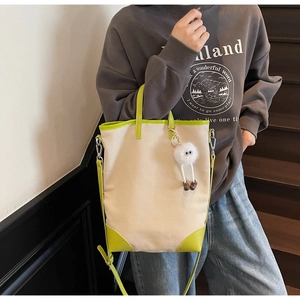 Detail of canvas tote bag with lime green leather trim and cute plush charm accessory