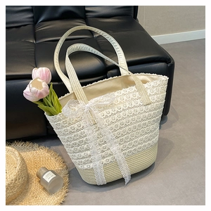 Close-up of white floral lace woven straw tote bag with a bow detail for summer
