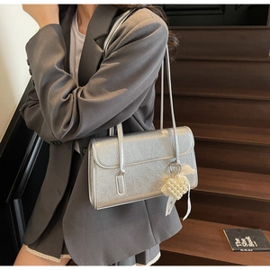 Detail of silver pleated shoulder bag with pearl heart pendant and lace ribbon accents