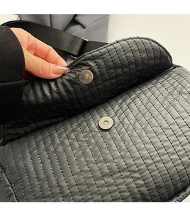 Detail of black quilted nylon saddle bag featuring a metallic magnetic disc buckle closure