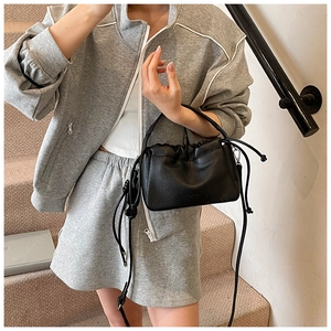 Fashionable black pleated crossbody bag styled on a staircase for a modern commuting look