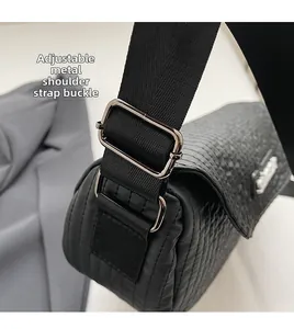 Close-up of adjustable nylon wide shoulder strap and metal buckle on black saddle bag