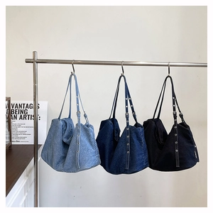 Close-up of three denim Hobo bags in blue and black with silver eyelet straps