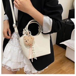 Detail of cream bucket bag with lychee texture leather and a cute brown bear charm