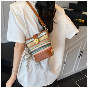 Detail of multi-color woven bucket bag with leather trim and star charm on a model