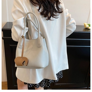 Détail du sac seau en cuir grainé gris clair avec un charmant pendentif éléphant marron