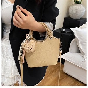 Detail of lychee pattern leather bucket bag with scarf and bear charm decoration