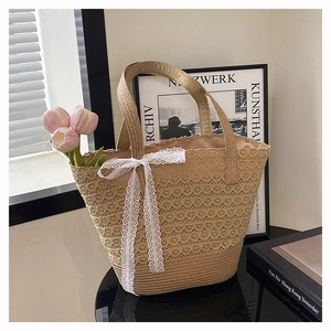 Detail of hand-woven straw beach bag with delicate white lace bow and hollow textures