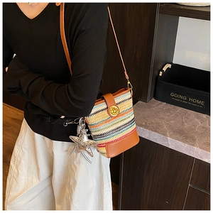 Detail of colorful woven bucket bag with brown leather trim and star charm on model