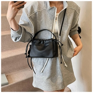 Close-up of black lychee grain leather drawstring bucket bag with top handle and strap