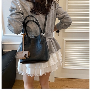 Détail du sac seau noir en cuir grainé avec un pendentif en forme d'éléphant marron chic