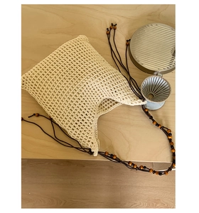 Détail du sac seau au crochet beige tissé main avec lanières marron et perles en bois