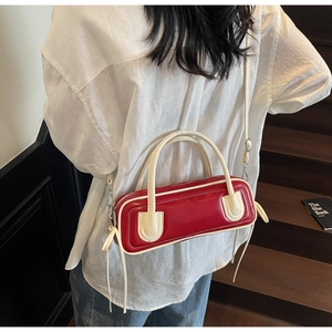 Detail of a red and cream contrast bowling bag worn as a shoulder bag on a model