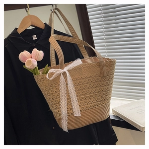Detail of straw woven tote bag featuring white lace bow and floral tulip decoration