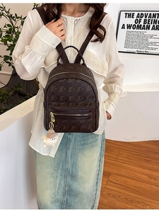 Brown embossed mini backpack with teddy bear pattern and plush sheep charm on white shirt