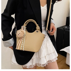 Detail of lychee pattern bucket bag with bear charm and scarf on a model