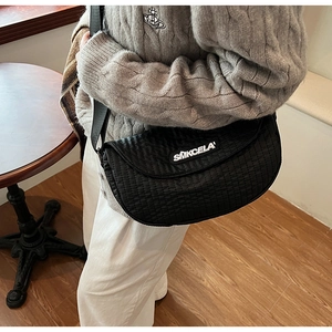 Close-up of black quilted crescent saddle bag with adjustable wide shoulder strap detail