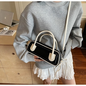 Close-up of contrast color baguette bag featuring elegant side tassel and metal buckles