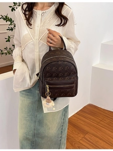 Deep brown embossed mini backpack with cartoon bear prints and a plush ball charm