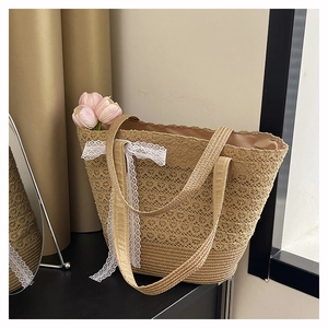 Detailed close-up of woven straw tote bag with elegant white lace trim and bow detail