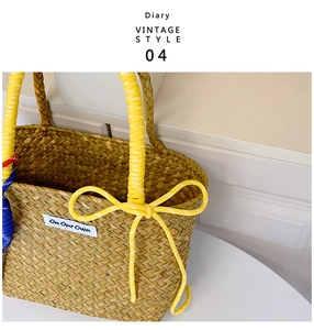Close-up of handmade straw bucket bag with yellow rope handle and decorative bow knot