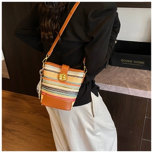 Detail of colorful woven bucket bag with brown leather base and silk scarf accessory