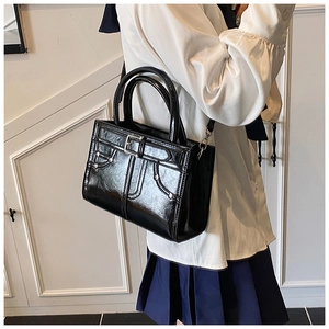 Détail d'un sac à main en cuir verni noir avec rivets argentés et boucle décor
