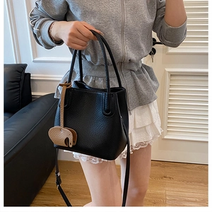 Détail d'un sac seau en cuir grainé noir avec un charmant pendentif éléphant marron