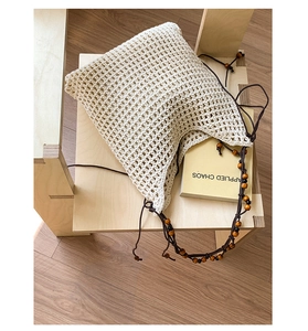 Gros plan du sac cabas en crochet blanc cassé avec cordon de serrage et billes en bois